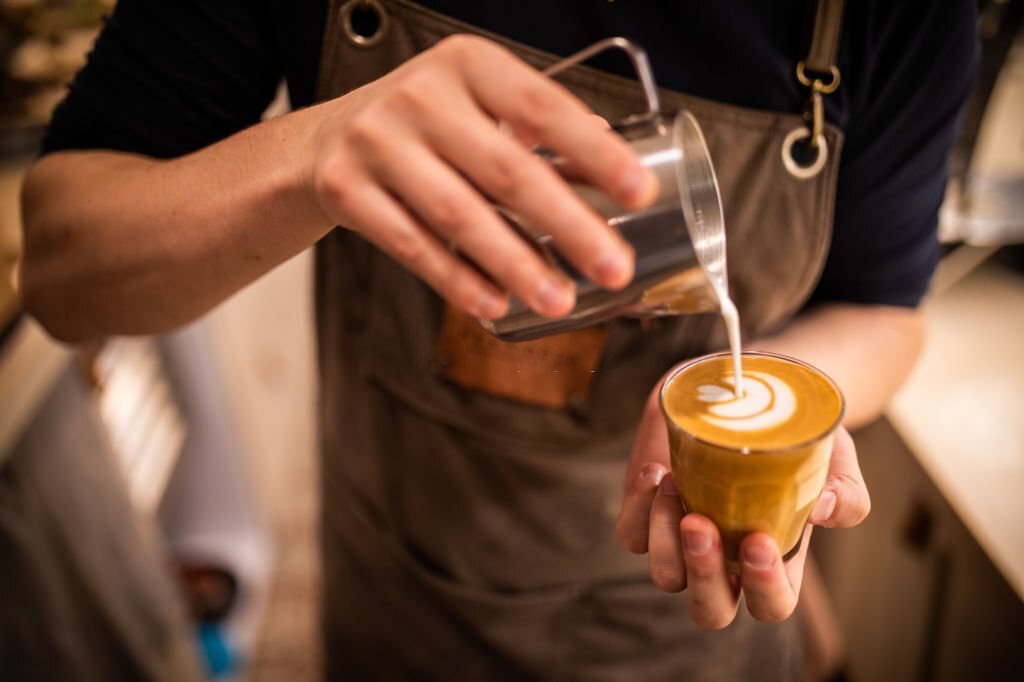 Barista sedang membuat secangkir latte art